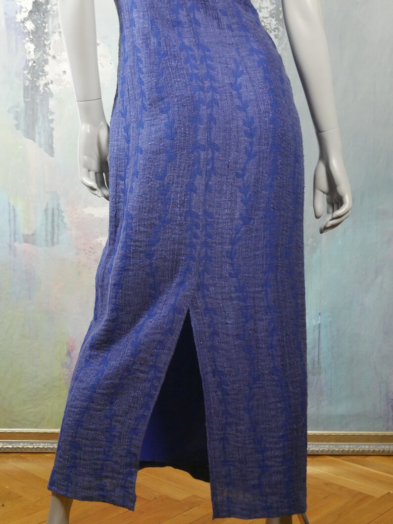 May include: A long, blue maxi dress with a floral pattern. The dress has a slit up the back and is made of a soft, flowing fabric.