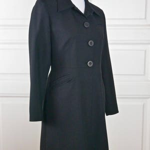 May include: A black long-sleeved jacket with a collar and four buttons down the front.