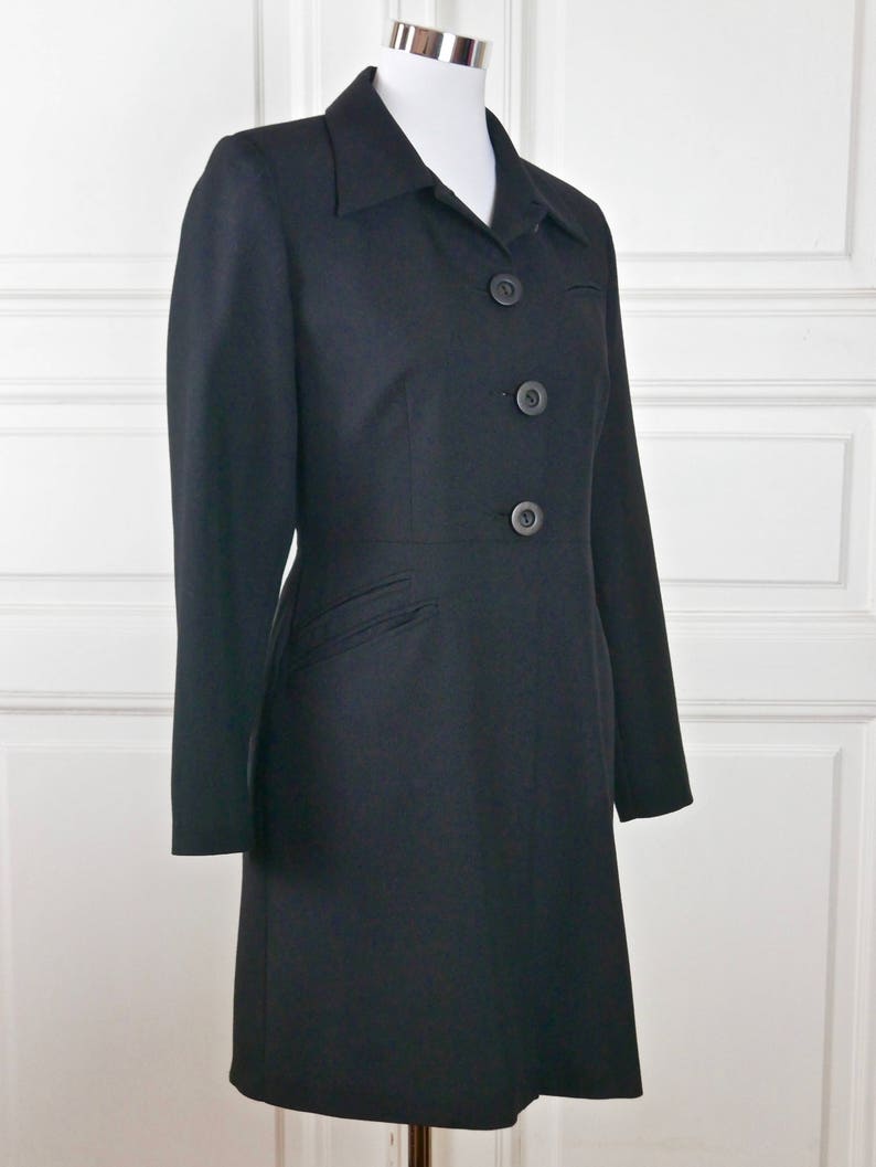May include: A black long-sleeved jacket with a collar and four buttons down the front.