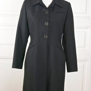 May include: A black long-sleeved coat with a collar and five buttons down the front.