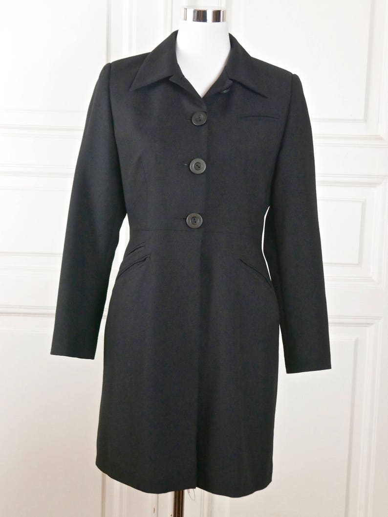 May include: A black long-sleeved coat with a collar and five buttons down the front.