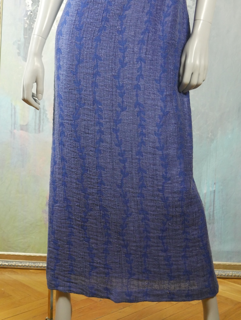 May include: A long, blue skirt with a floral pattern. The skirt is made of a textured fabric and has a simple, elegant design.
