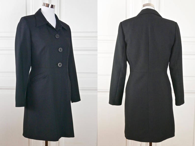 May include: A black long-sleeved coat with a collar and three buttons down the front. The coat has a fitted waist and a straight skirt.