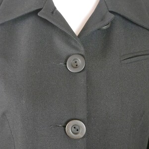 May include: Close-up of a black blazer with two black buttons. The blazer has a classic, tailored look.