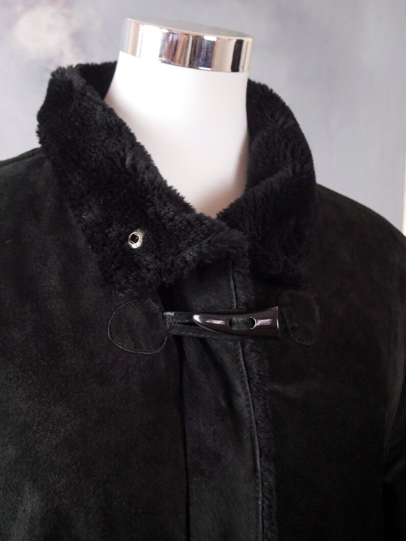 May include: A black suede jacket with a faux fur collar and a black toggle closure.