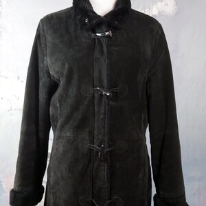 May include: A long black suede coat with a faux fur collar and cuffs. The coat has a toggle closure and is lined with a soft fabric.