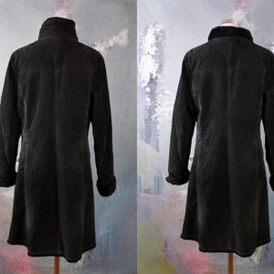 May include: A black suede jacket with a faux fur collar and cuffs. The jacket has a long, A-line silhouette and a zipper closure.