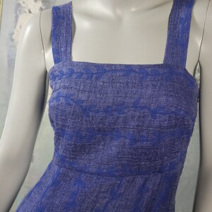 May include: A sleeveless dress with a square neckline and a blue and white floral pattern. The dress is made of a textured fabric and has a fitted bodice and a flowing skirt.