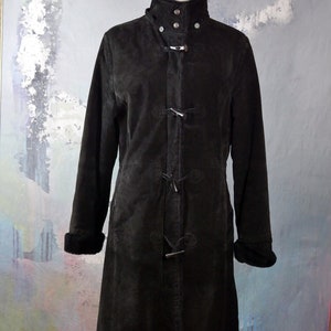 May include: A black suede coat with a high collar, toggle closures, and a fur-lined collar and cuffs.
