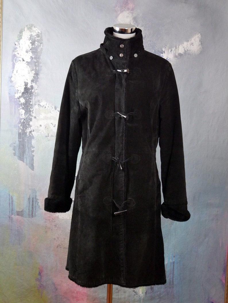 May include: A black suede coat with a high collar, toggle closures, and a fur-lined collar and cuffs.