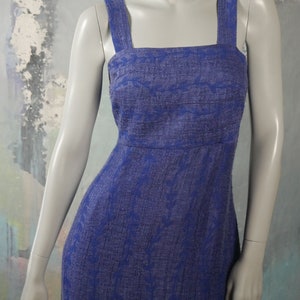 May include: A long, sleeveless dress with a square neckline and a floral pattern. The dress is made of a textured fabric and is a deep blue color.