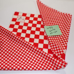 May include: A red and white checkered fabric square featuring the signature John Weitz. A light green adhesive note is attached to the fabric with the handwritten text W 518 Weitz 27 x 27 inches, indicating the dimensions of the textile piece.
