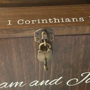 May include: A wooden box with a lock and key. The box has the text "1 Corinthians" and "am and" on it.