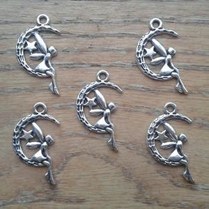 May include: Five silver charm pendants featuring a fairy sitting on a crescent moon with a star. Each pendant has a loop at the top for attaching to a chain or bracelet.
