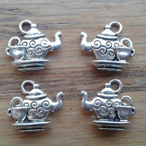 May include: Four silver charm pendants shaped like teapots with a cup and saucer. Each teapot has a swirl design.