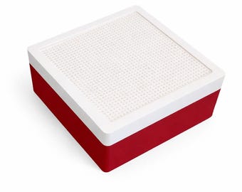 May include: A red and white square storage box. The box has a white, perforated top and a red base. The top is framed with a white border. The box is designed to hold small items.