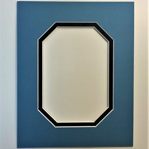 May include: A rectangular picture frame mat with a white border, a blue center, and an octagonal opening. The opening is framed with a black and white border. The mat is designed for displaying photographs or artwork.