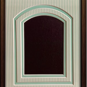 May include: A brown wooden picture frame with a white and green striped mat. The mat has a double arch design with a black background.