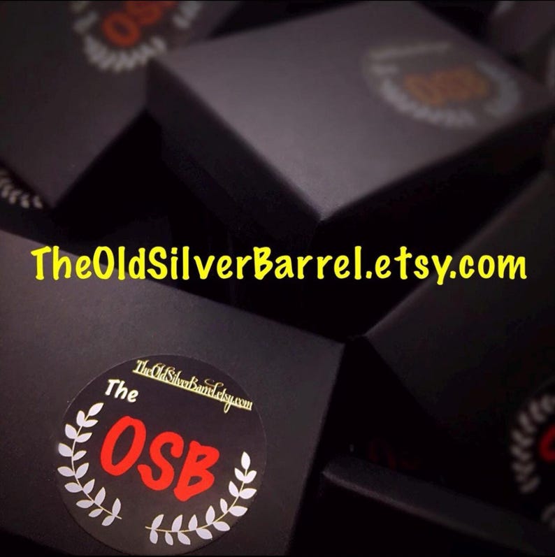 May include: A collection of black boxes, some with circular stickers featuring the text "The OSB" in red, surrounded by a white laurel wreath. The website address "TheOldSilverBarrel.etsy.com" is displayed in yellow.