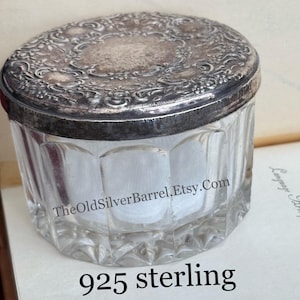 May include: A clear glass jar with a silver lid featuring an ornate design. The lid is marked "925 sterling".