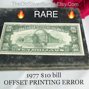 May include: A rare 1977 $10 bill with an offset printing error. The bill features a green background with a picture of the Treasury Building in Washington, D.C. and the text "THE UNITED STATES OF AMERICA" and "IN GOD WE TRUST".