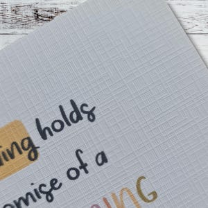 May include: Close-up of a card with the text "The ending holds the promise of a" printed in black. The word "ending" is highlighted in a yellow rectangle.