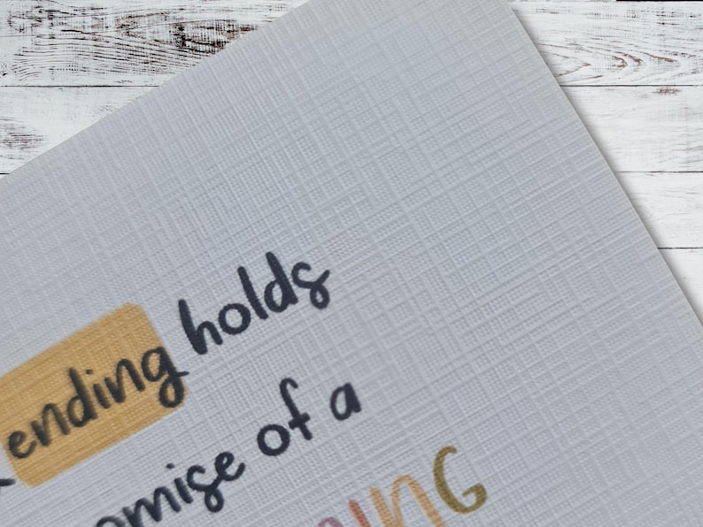 May include: Close-up of a card with the text "The ending holds the promise of a" printed in black. The word "ending" is highlighted in a yellow rectangle.