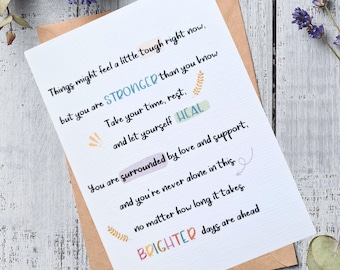 Può includere: Un biglietto di auguri bianco con testo motivazionale in vari colori, tra cui blu, verde e arancione. Il biglietto è all'interno di una busta marrone ed è circondato da rametti di lavanda. Il testo include frasi come "STRONGER than you know" e "BRIGHTER days are ahead."