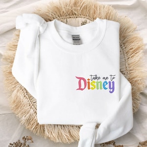 May include: White sweatshirt with a rainbow coloured "Take me to Disney" graphic.