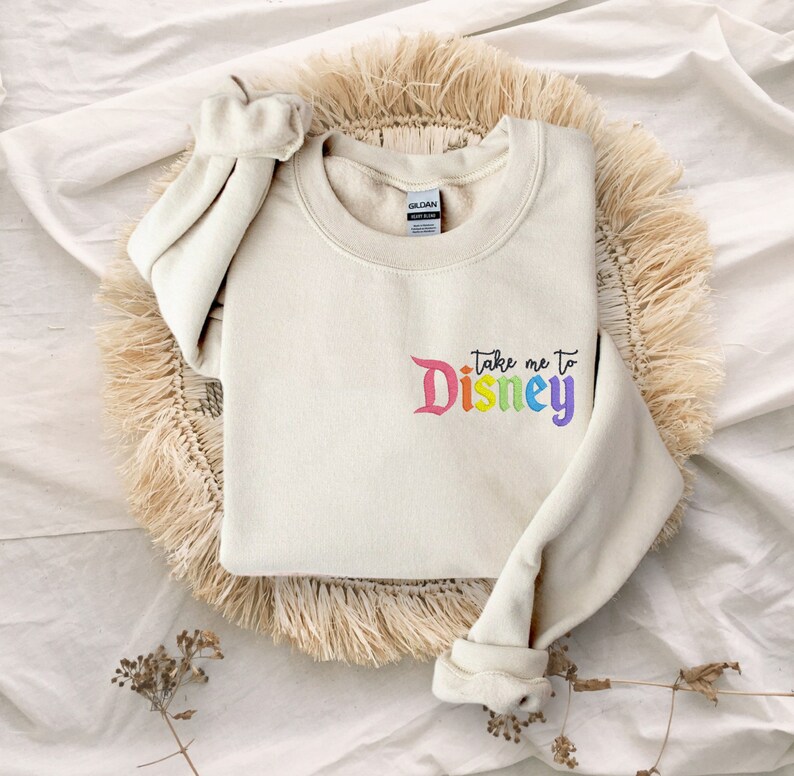 May include: A cream coloured sweatshirt with the text "Take me to Disney" in rainbow colours.