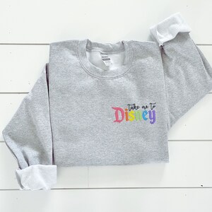 May include: Grey sweatshirt with the text "Take me to Disney" in rainbow colours.