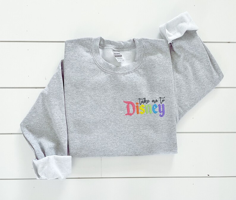 May include: Grey sweatshirt with the text "Take me to Disney" in rainbow colours.