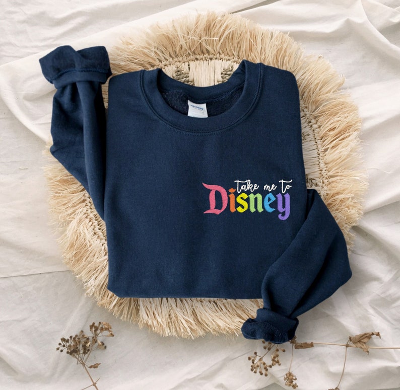 May include: Navy blue sweatshirt with a rainbow coloured "Take me to Disney" graphic on the front.