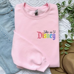 May include: Pink sweatshirt with the text "Take me to Disney" in rainbow colours.