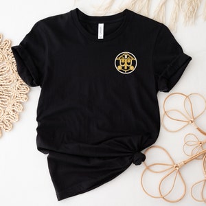 May include: Black t-shirt with a gold embroidered logo of a stylized house with a roof and the letters "UP" inside.