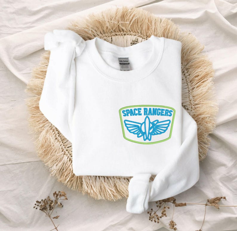 May include: White sweatshirt with a blue and green embroidered patch that says "Space Rangers" with a rocket ship inside.