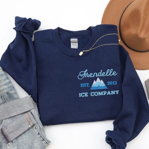 Könnte beinhalten: Marineblauer Sweatshirt mit einer weißen Grafik einer Bergkette und dem Text "Aredelle Est. 2013 Ice Company".