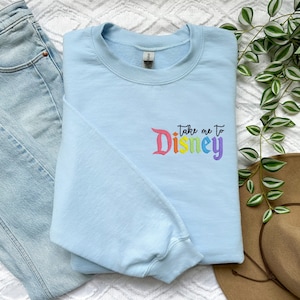 May include: A light blue sweatshirt with the text "Take me to Disney" in rainbow colours.