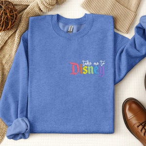May include: A blue sweatshirt with the text "Take me to Disney" in rainbow colours.