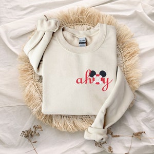 May include: A cream-colored sweatshirt with a red embroidered design that says "ahoy" with a Mickey Mouse head wearing a life preserver.