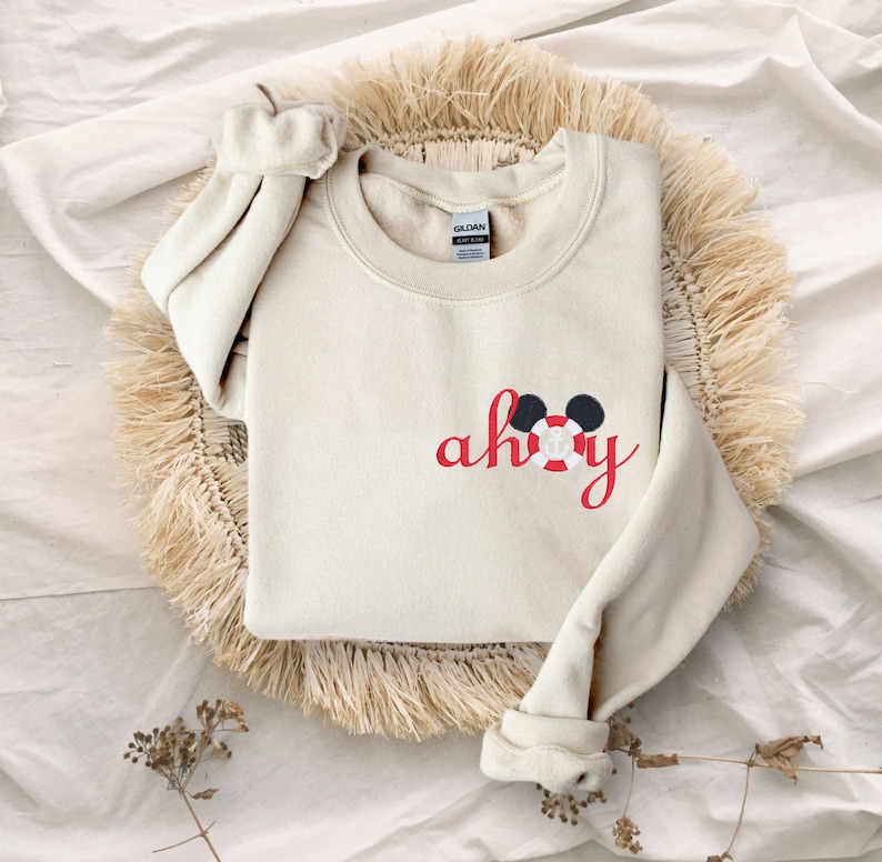May include: A cream-colored sweatshirt with a red embroidered design that says "ahoy" with a Mickey Mouse head wearing a life preserver.