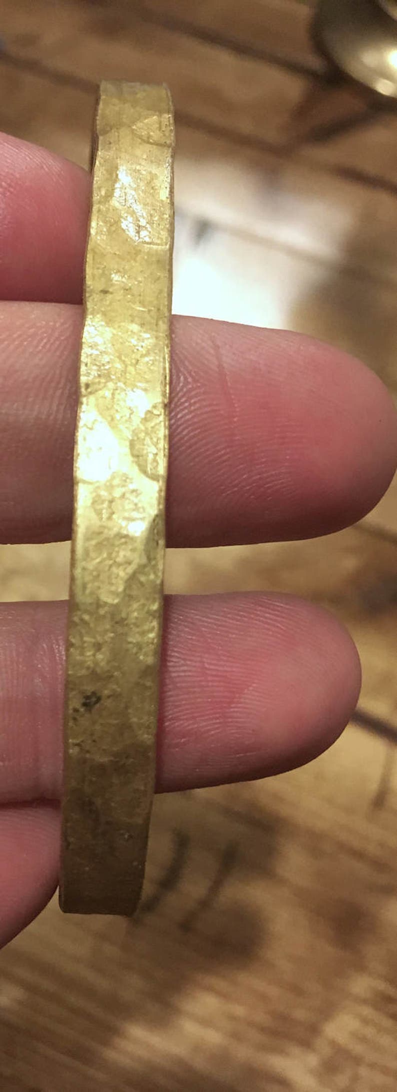 May include: A gold-colored metal bracelet with a hammered texture.
