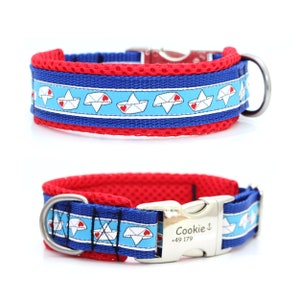 Könnte beinhalten: Blau-rotes Hundehalsband mit einem Muster aus Papierbooten mit roten Herzen. Das Halsband hat eine Metallschnalle und einen D-Ring. Auf dem Halsband stehen der Name "Cookie" und eine Telefonnummer.