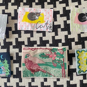 May include: A white ceramic mug with a black handle and the text "But First, Coffee" in a bold, black font. The mug is filled with a dark liquid, probably coffee, and rests on a light-coloured surface.