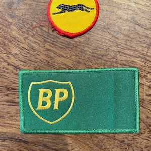 May include: Two vintage patches. One is round with a yellow background, a black panther, and a red border. The other is rectangular, green with a yellow shield containing the letters "BP".
