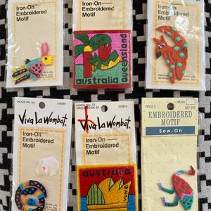 May include: A selection of Viva la Wombat iron-on embroidered motifs. The patches feature Australian designs, including a kangaroo, a snake, and the word "Sydney". Each patch is packaged on a card.