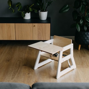 May include: A white wooden high chair with a removable tray. The chair has a simple design and is made of natural wood.