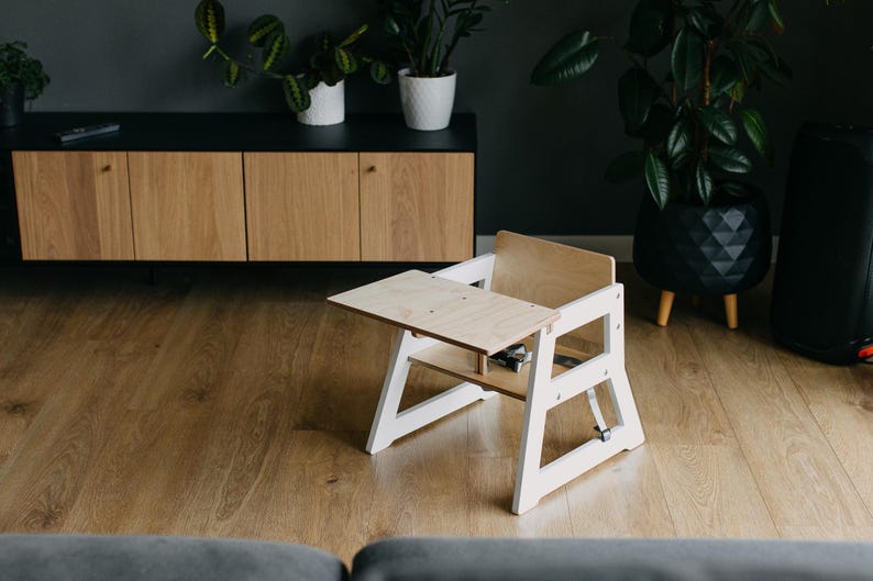 May include: A white wooden high chair with a removable tray. The chair has a simple design and is made of natural wood.