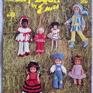 May include: A vintage "Dolly Book by Emu" cover showing dolls in handmade outfits. The dolls are dressed in crochet and knitted garments, set against a backdrop of hay. The cover also has text.