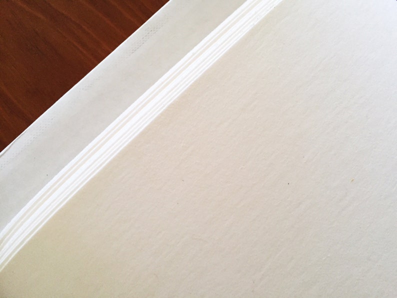 May include: A close-up of a white, textured surface with a slightly raised edge. The surface is smooth and appears to be made of paper or cardstock.